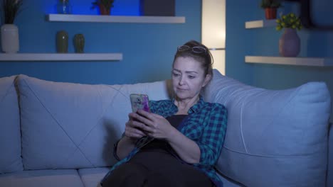 Woman-lying-on-the-sofa-at-night-texting-on-the-phone.-Happy-and-in-good-spirits.